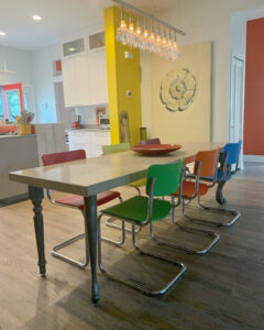 A long shot of the dining table with colorful chairs